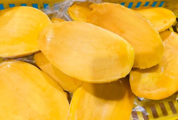 Gelbe Mangoscheiben in einem Behälter, frisch und saftig.